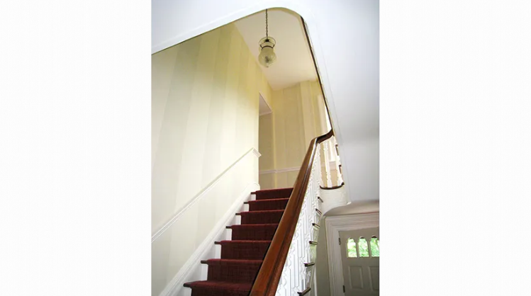 A staircase with a red carpet and a white railing