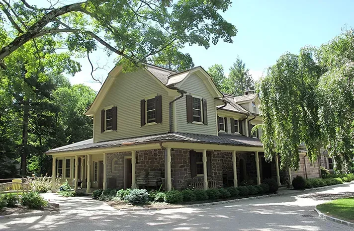 A large house with a porch and trees in the background