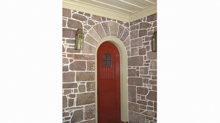 A red door is surrounded by a stone wall.