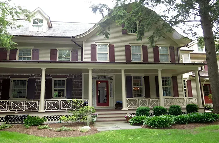 A large house with a large porch and a red door