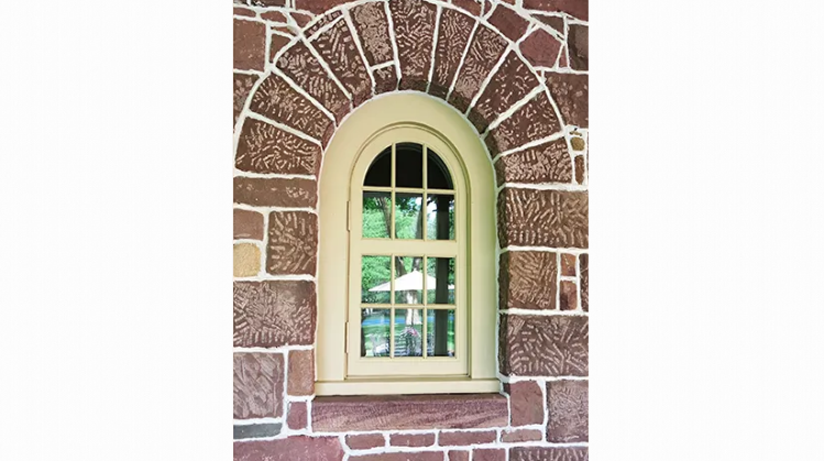 A brick wall with a window in the middle of it