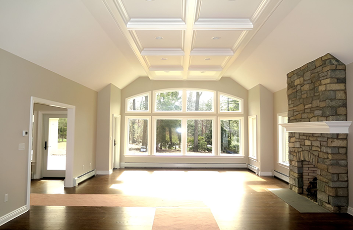 An empty living room with a fireplace and lots of windows