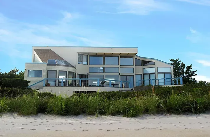 A large house is sitting on top of a sandy beach