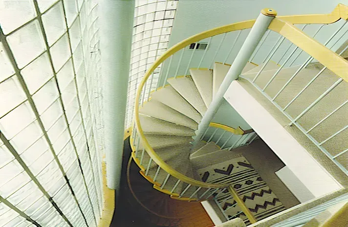 A spiral staircase in a building with a yellow railing