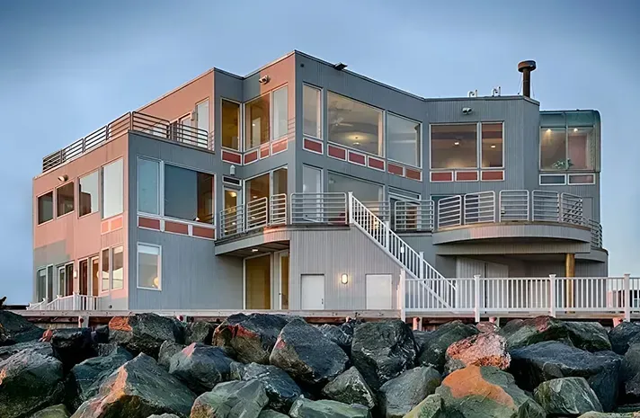 A large building with a lot of windows is surrounded by rocks.