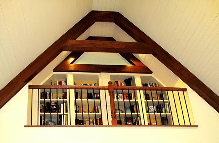 An attic with a staircase and shelves filled with books