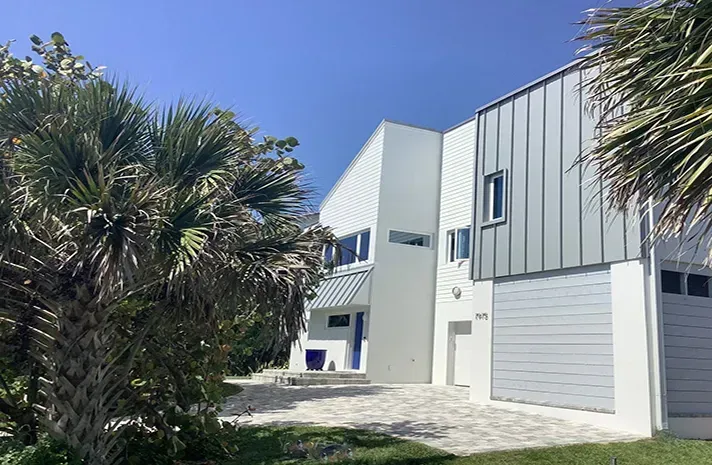 A large white house with a garage and palm trees in front of it