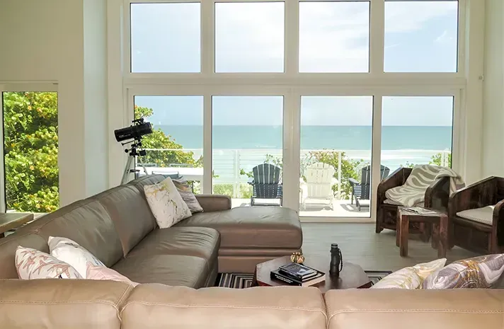 A living room with a couch and chairs and a view of the ocean.