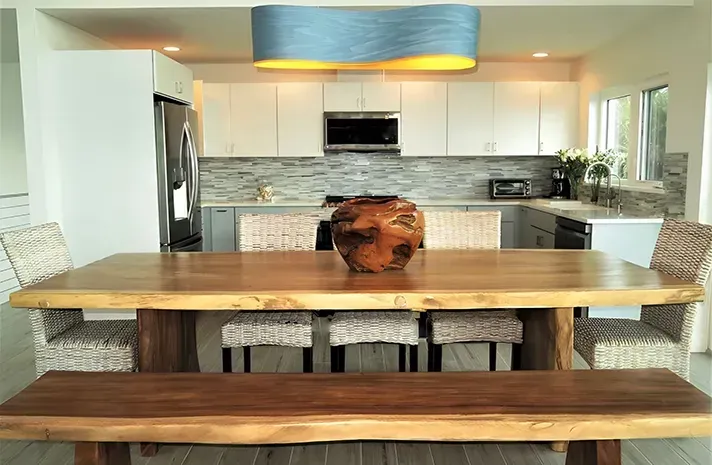 A dining room table with a vase on top of it in a kitchen.