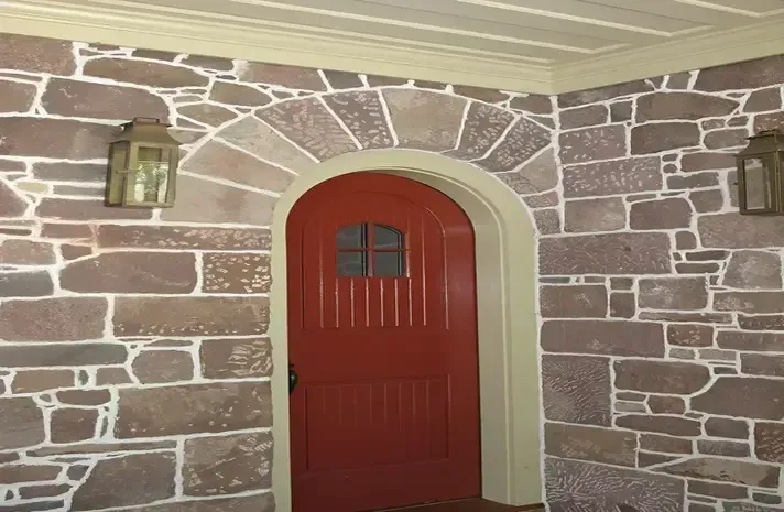 A red door is surrounded by a stone wall