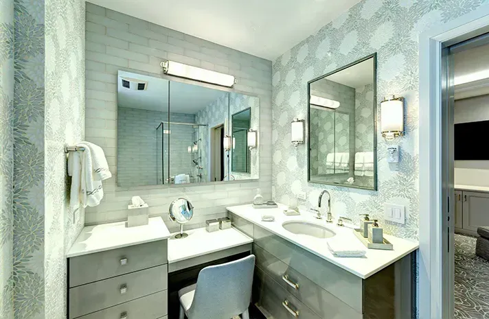 A bathroom with two sinks , two mirrors , a toilet and a vanity.