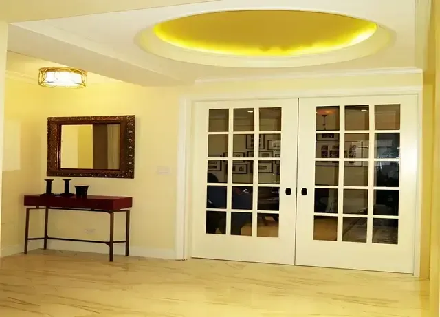 A hallway with french doors and a mirror on the wall