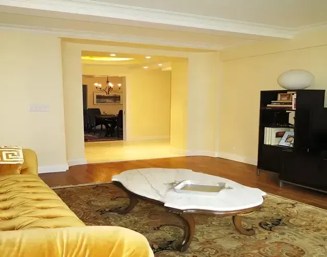 A living room with a yellow couch and a white coffee table