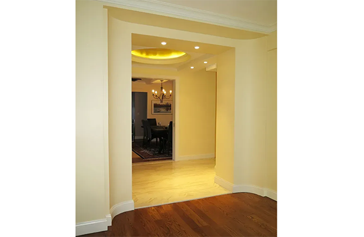 An empty room with a wooden floor and a doorway leading to a dining room.