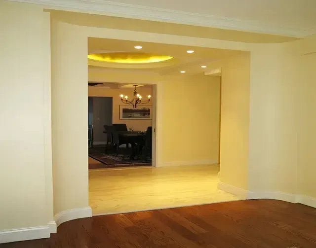 An empty room with a doorway leading to a dining room