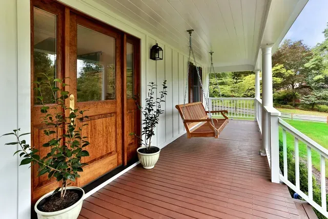 A porch with a swing and potted plants on it