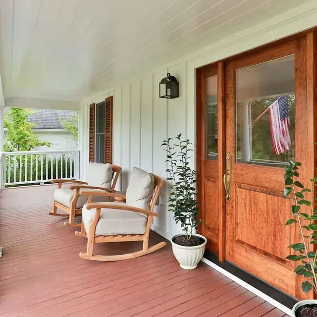 A porch with rocking chairs and a potted plant