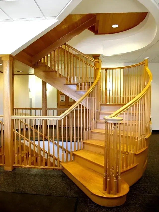 A wooden spiral staircase with a white railing