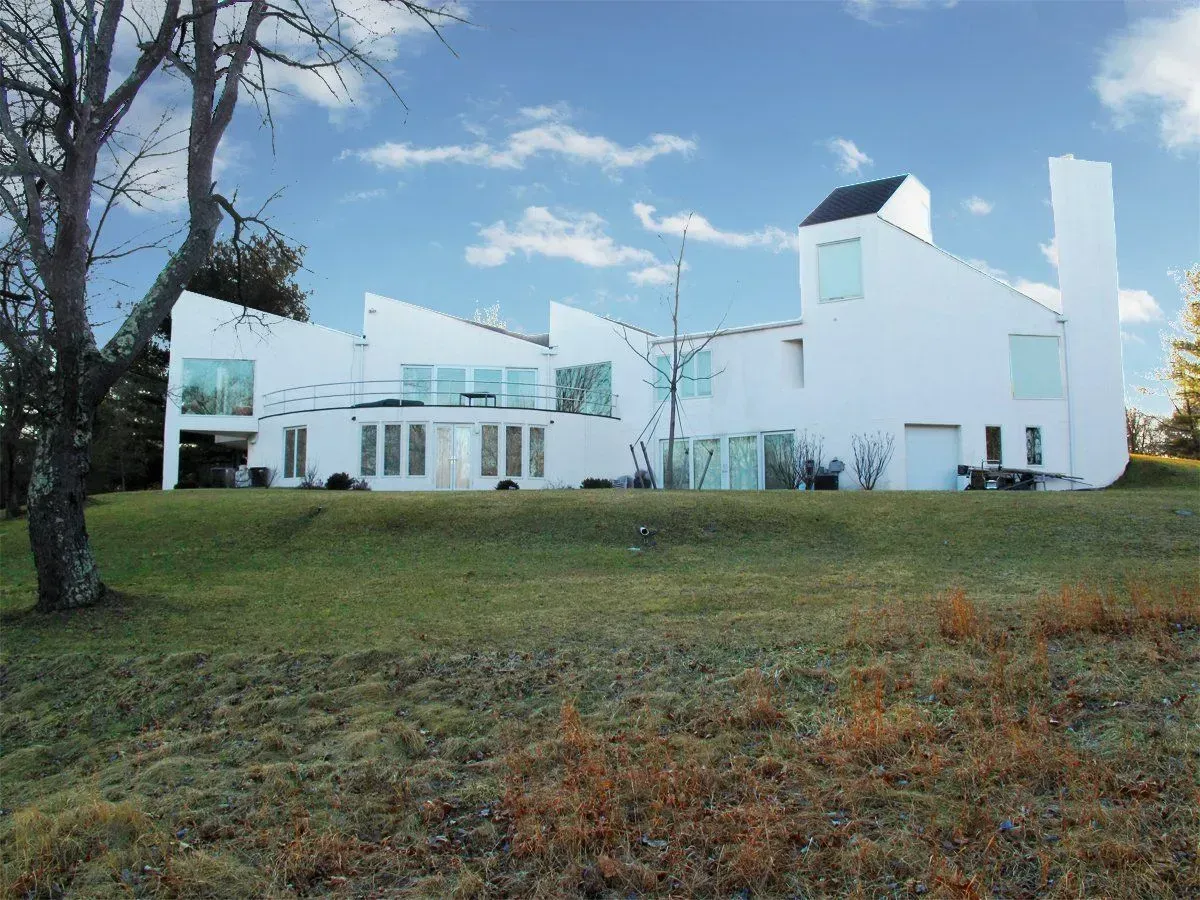 A large white house sits on top of a grassy hill