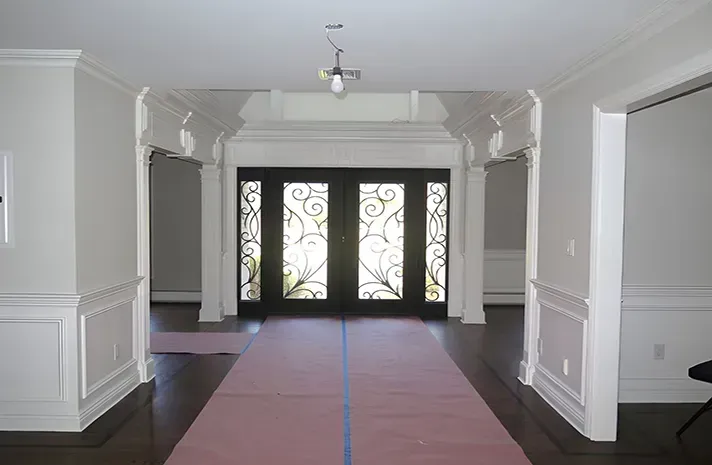 A hallway with a pink carpet and a black door