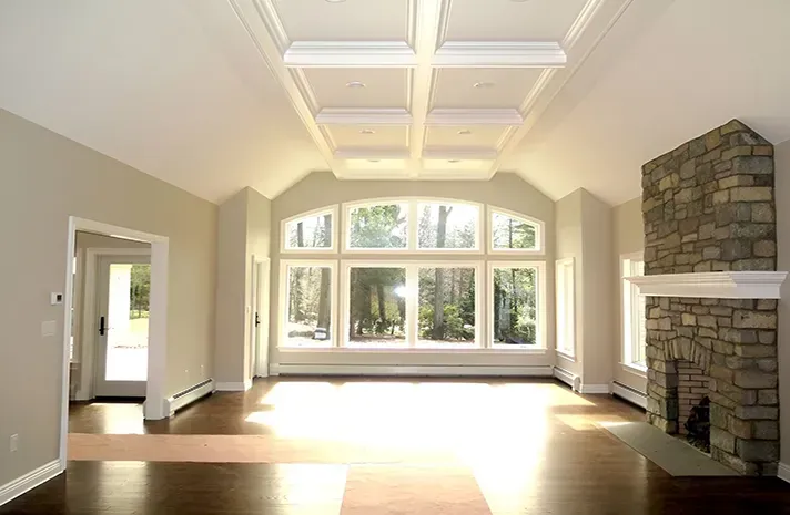 An empty living room with a fireplace and lots of windows