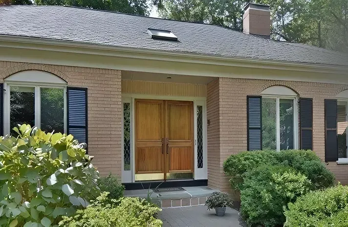 A brick house with a wooden door and black shutters