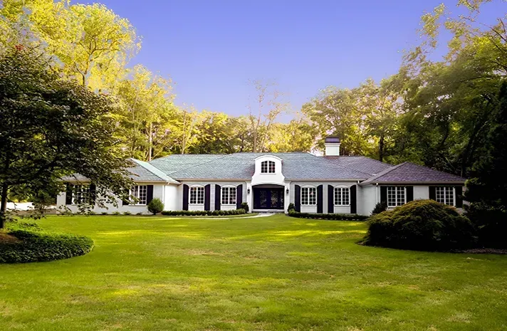 A large white house with a blue roof and black shutters