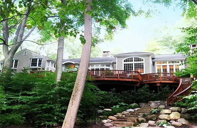 A large house with a large deck in the woods