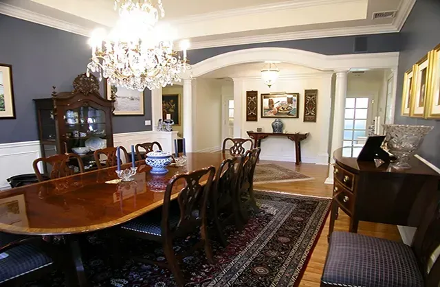 A dining room with a long table and chairs and a chandelier.
