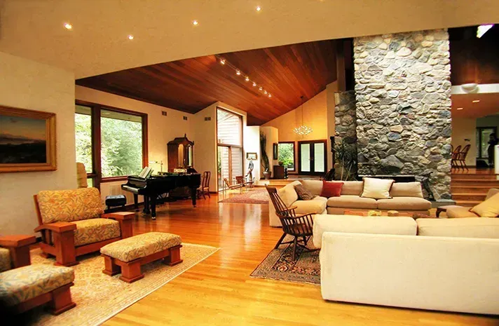 A living room with a piano and a stone fireplace