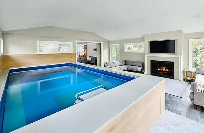 There is a large indoor swimming pool in the middle of a living room.