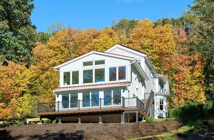 A large white house is sitting on top of a hill in the middle of a forest.