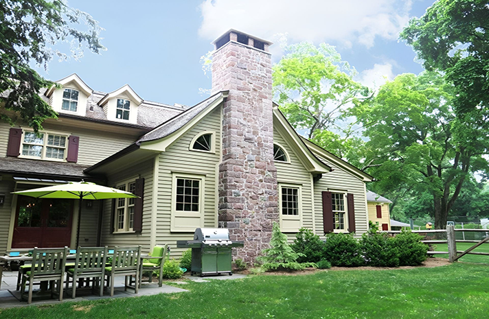 A large house with a brick chimney and a grill