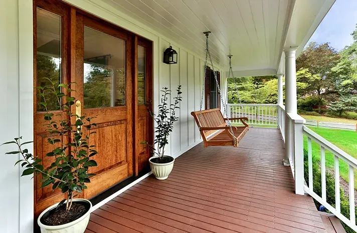 A porch with a swing and potted plants on it