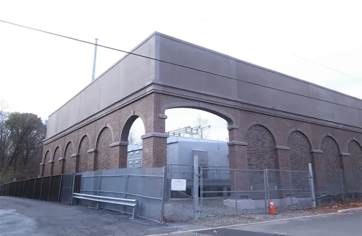 A large brick building with arches and a fence around it