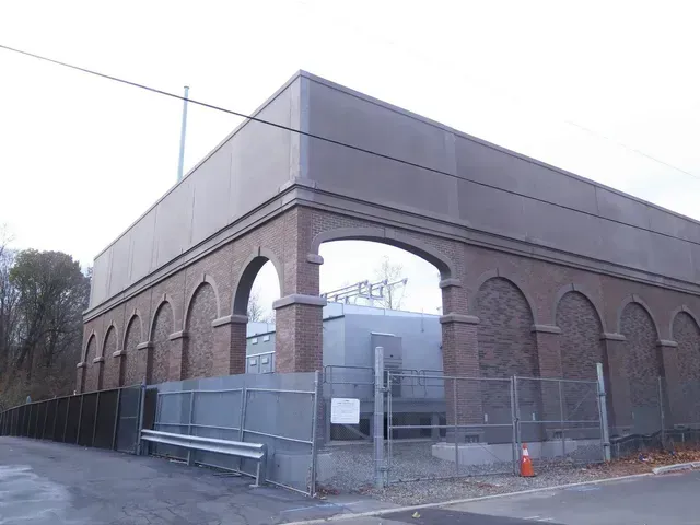 A large brick building with arches and a fence around it