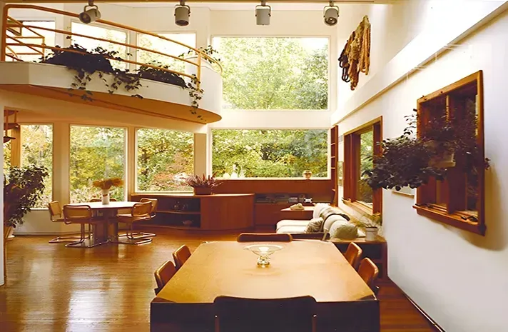 A living room with a table and chairs and lots of windows