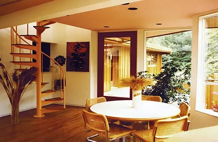 A living room with a spiral staircase and a table and chairs