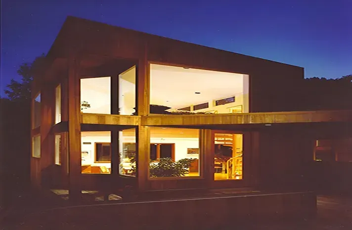 A house with a lot of windows is lit up at night