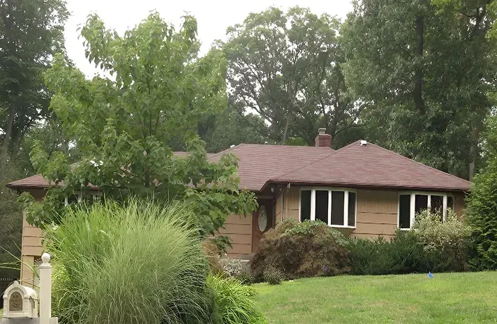 A house with a brown roof is surrounded by trees and grass