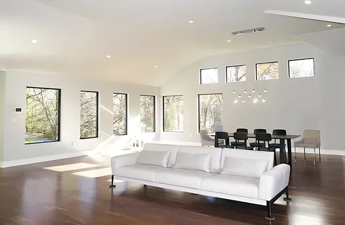 A living room with a white couch , dining table and chairs.