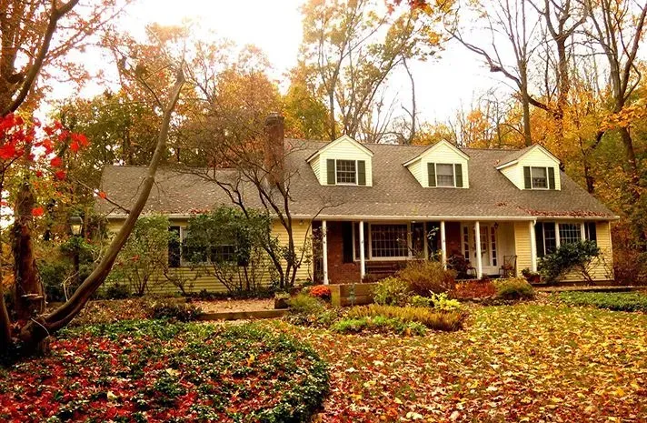 A house with a porch and a lot of leaves on the ground