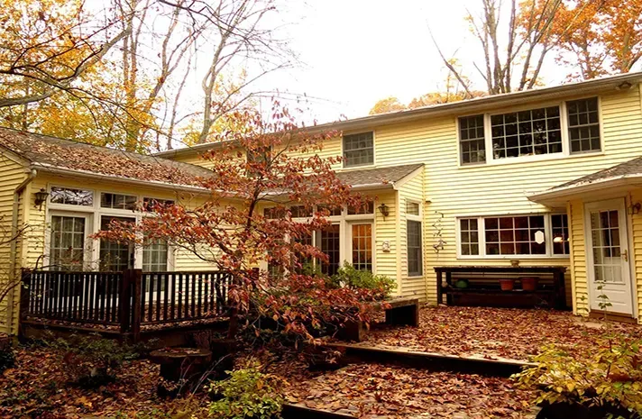 A large yellow house with a deck and a lot of windows