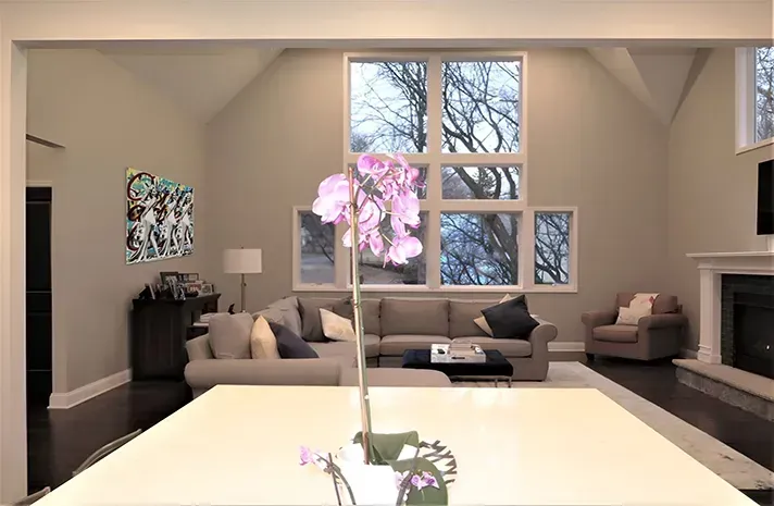 A living room with a couch and a fireplace and a vase of flowers on a table.