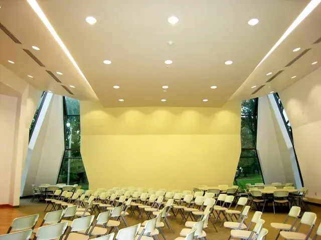 Rows of chairs in a large room with a yellow wall
