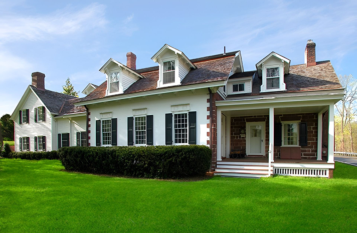 A large white house with black shutters and a porch