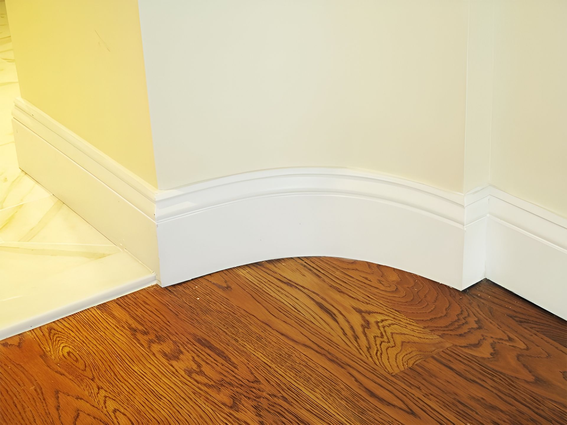 A corner of a room with hardwood floors and white molding