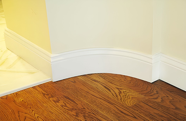 A wooden floor with white molding and a white wall