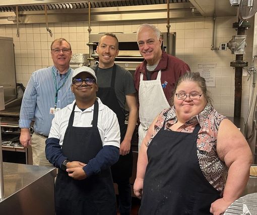 A group of people are posing for a picture in a kitchen.