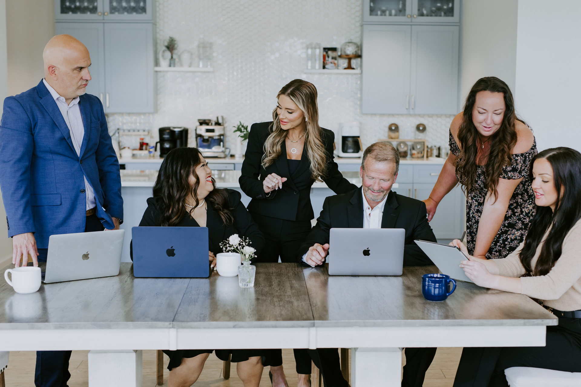 The Stafford Solutions team of six collaborating around a kitchen island with laptops in College Grove, Tennessee